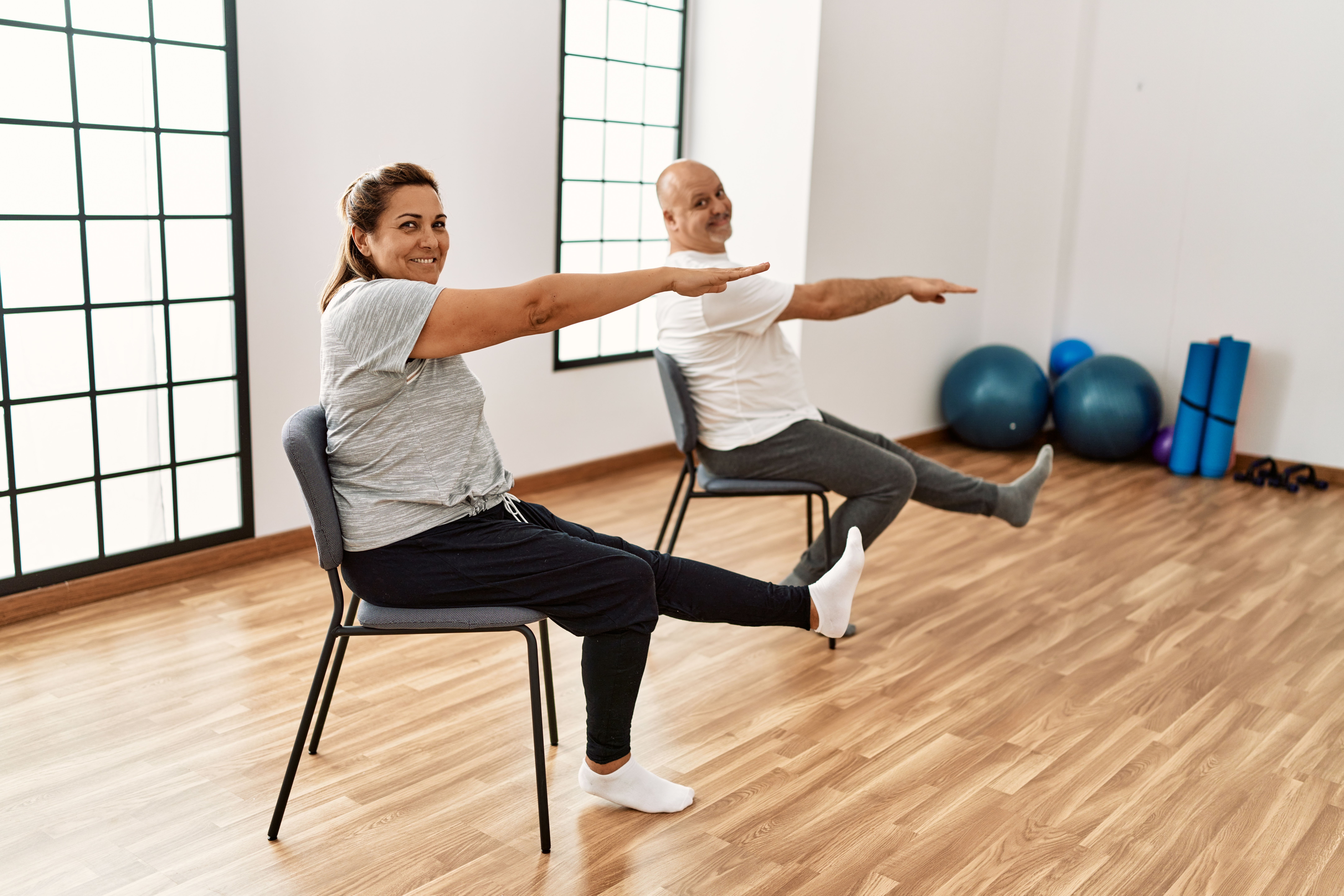 Two adults participate in Chair Yoga inside a studio