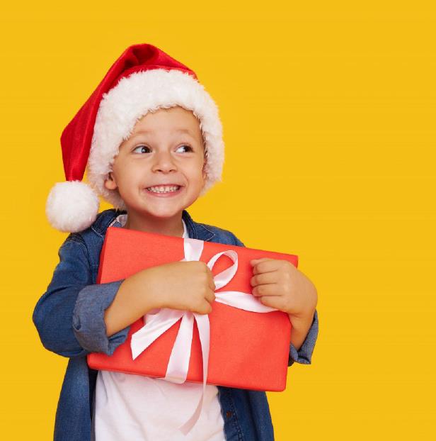 A child with a Santa hat on holds a Holiday gift